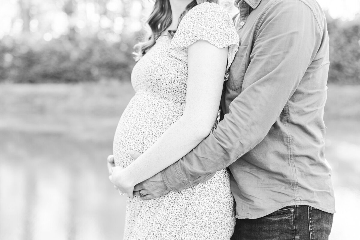 close up of a man with his arms around his pregnant wife's stomach