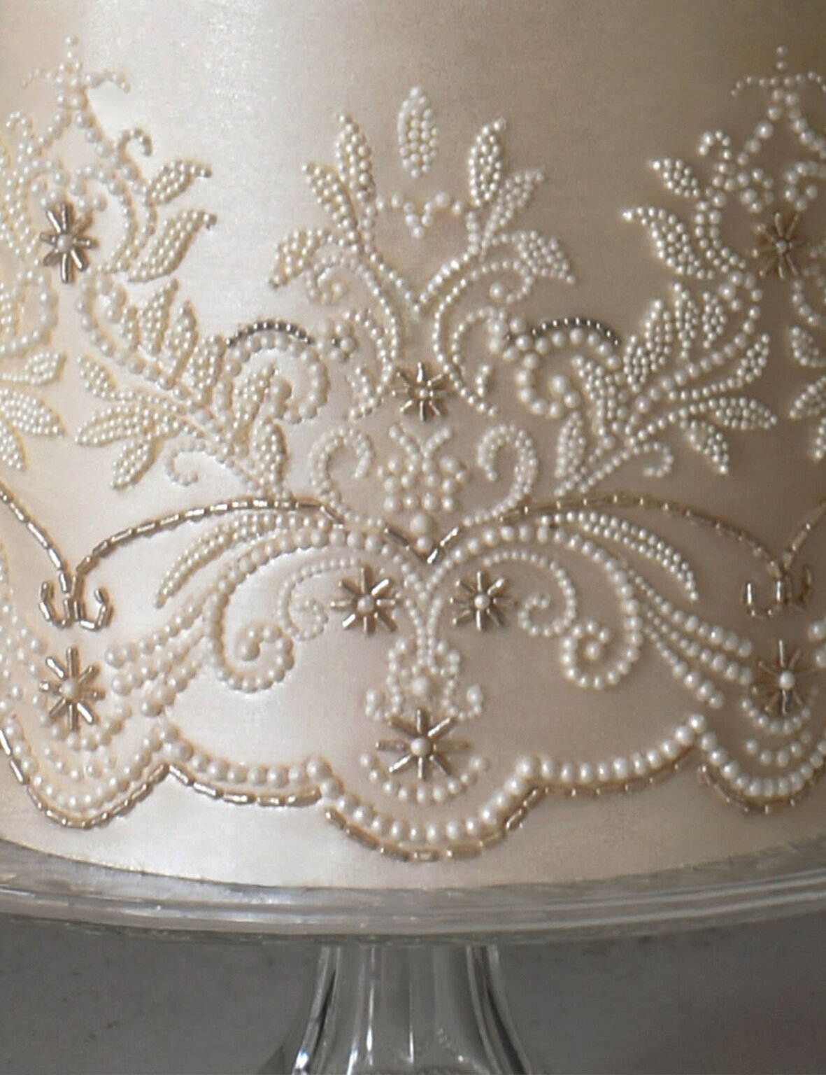 Intricate beaded lace detail and hand placed pearls on a satin sheen wedding cake