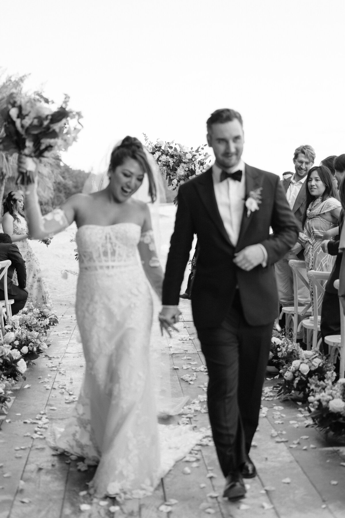 Bride and groom out of focus film photo walking down the aisle cheering after first kiss