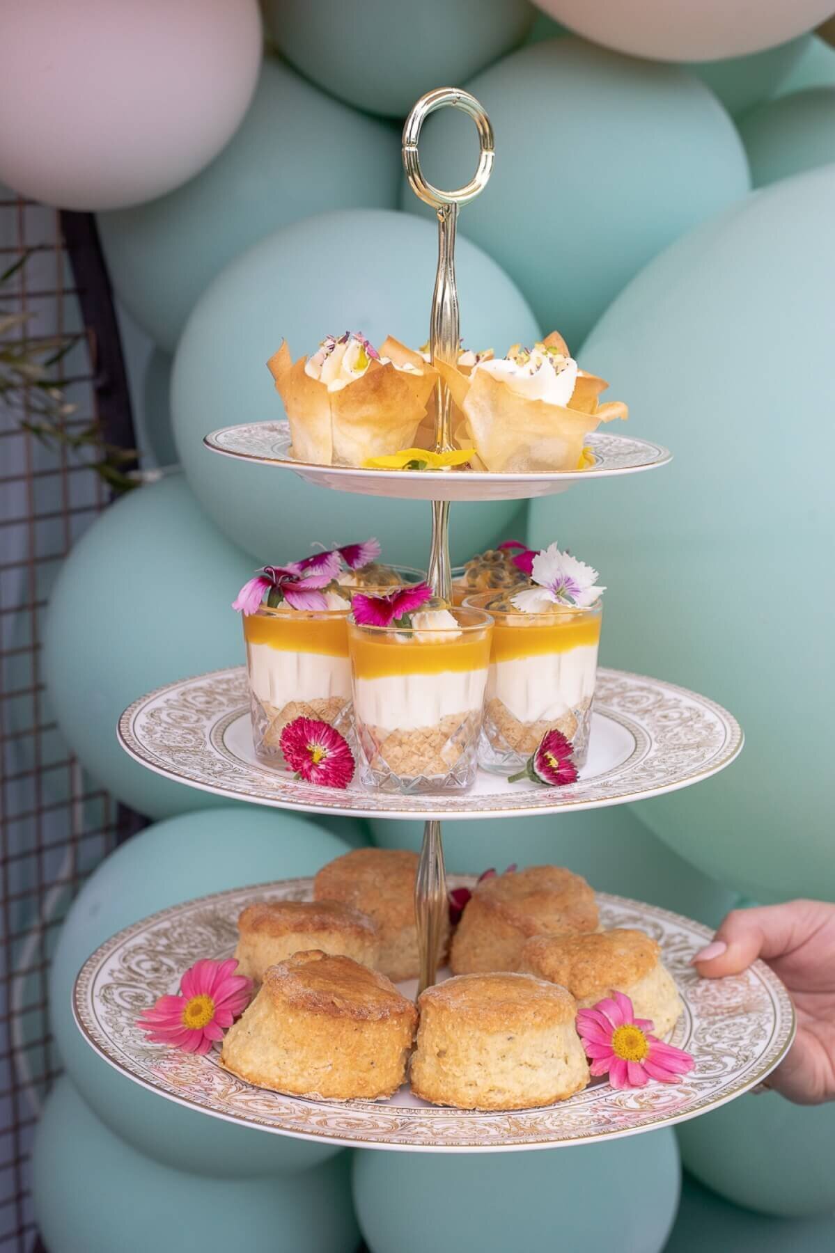 Balloon backdrop with cake stand filled with desserts and scones