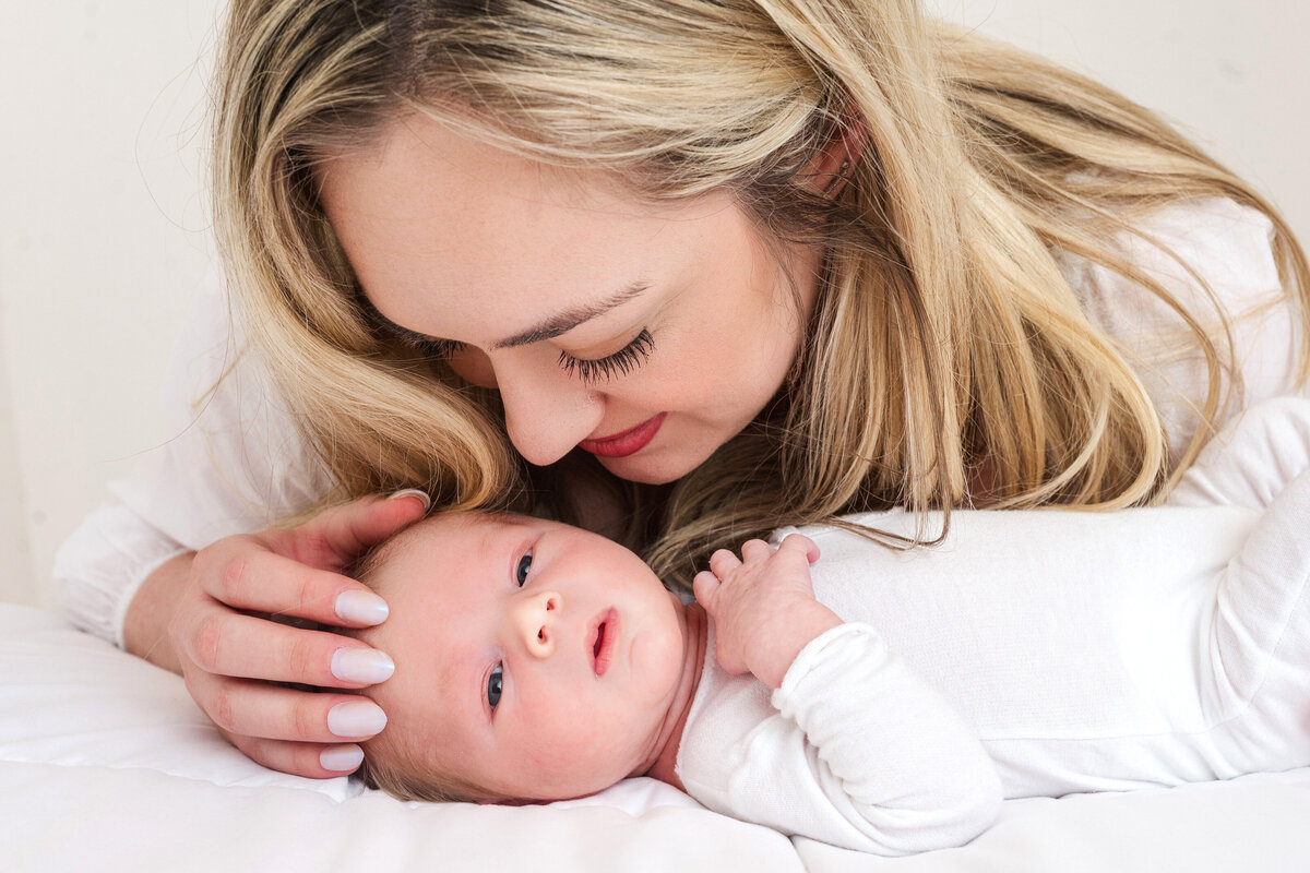 mom looking beautiful snuggling newborn baby