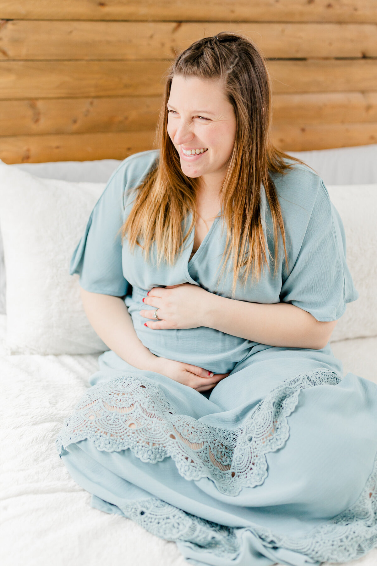 Pregnant woman laughing on bed