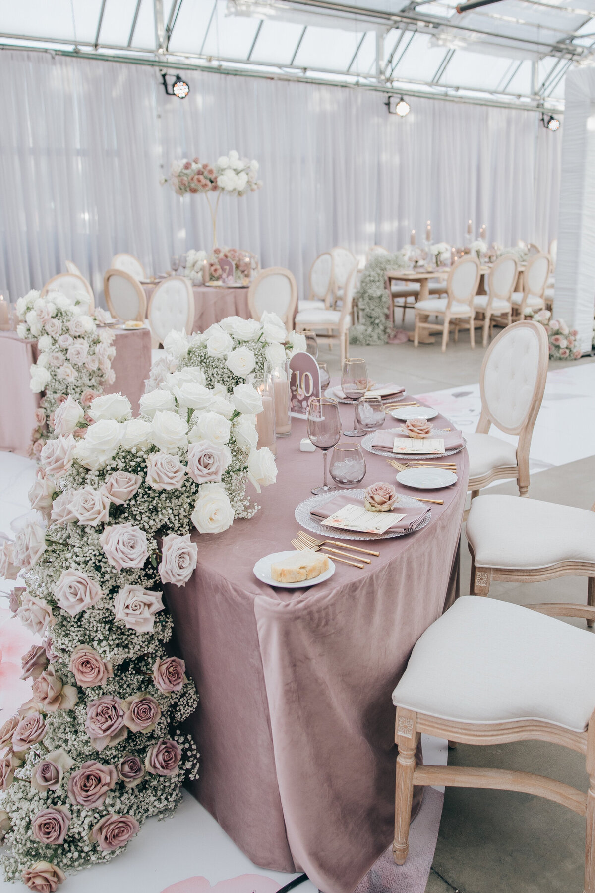 Beautiful blush roses and baby's breath draped over wedding dinner tables