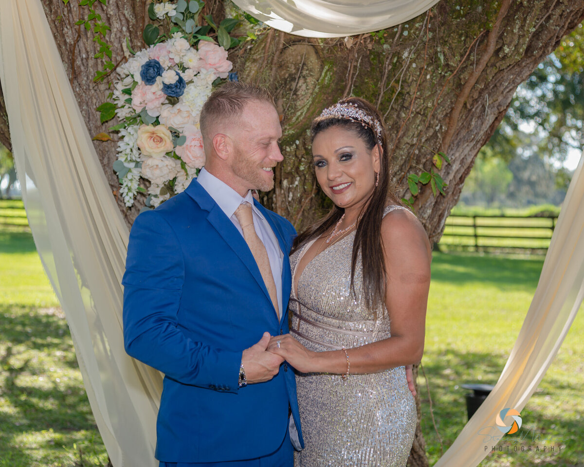 Newlyweds pose in front of a tree for wedding photos.