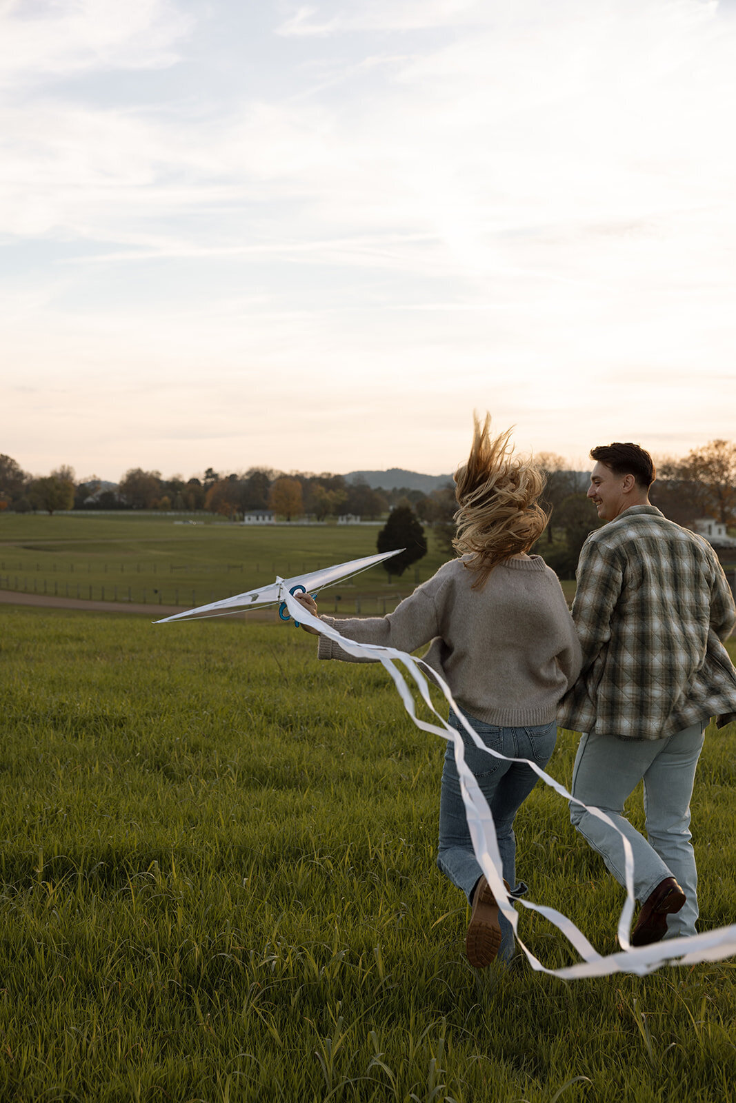 Couple flies kite during a candid engagement session at Harlinsdale Farm in Franklin, TN.