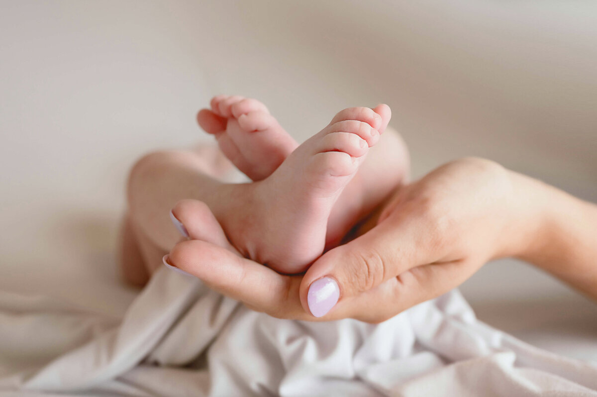 Newborn baby fit on blankets and gentely cradled in mom's hand.