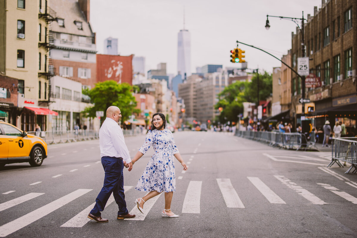 A couple walking through the crosswalk in the village in nyc during their engagement session
