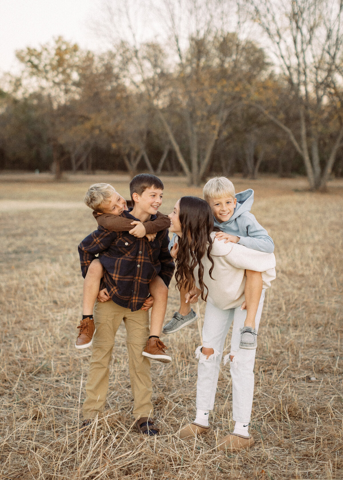 older brother and sister hold younger brothers on their backs during family photos at lee lake