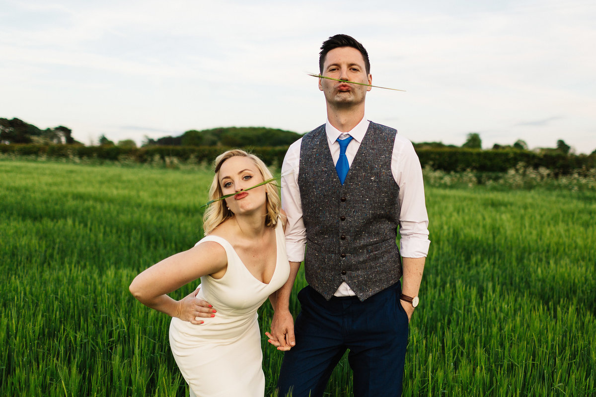 Bride and groom pulling a funny face with wheat on their lips in Yorkshire