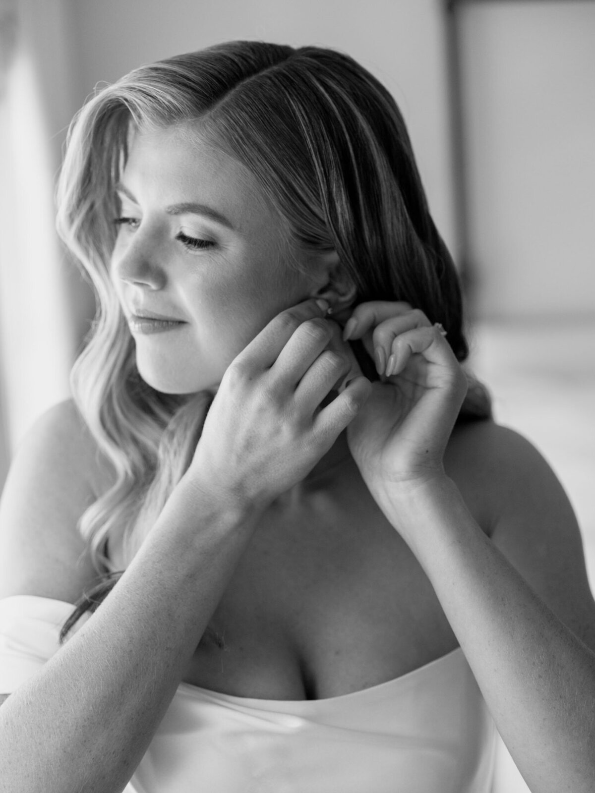 Bride getting ready by putting her earrings in