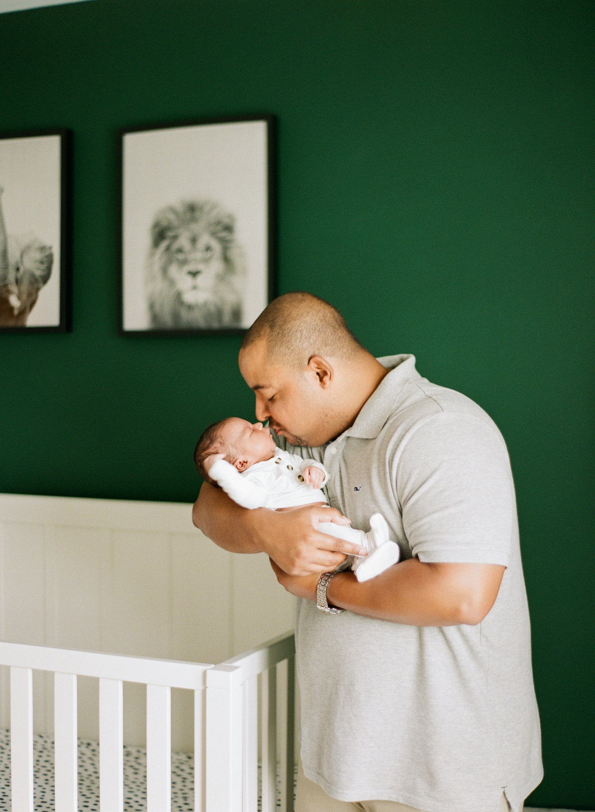 Black dad holding a black baby and kissing him on the nose during a Raleigh NC newborn session. Photographed by newborn photographers Raleigh A.J. Dunlap Photography.