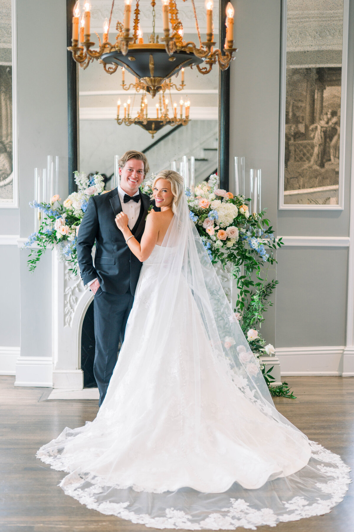 Bride and groom posed in front of colorful florals in the historic University Club building in Tuscaloosa
