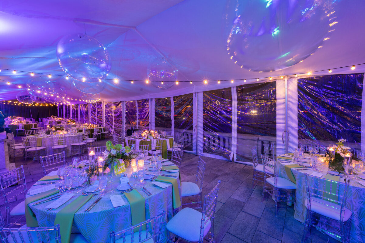 Purple-lit wedding tent setup with elegant table arrangements
