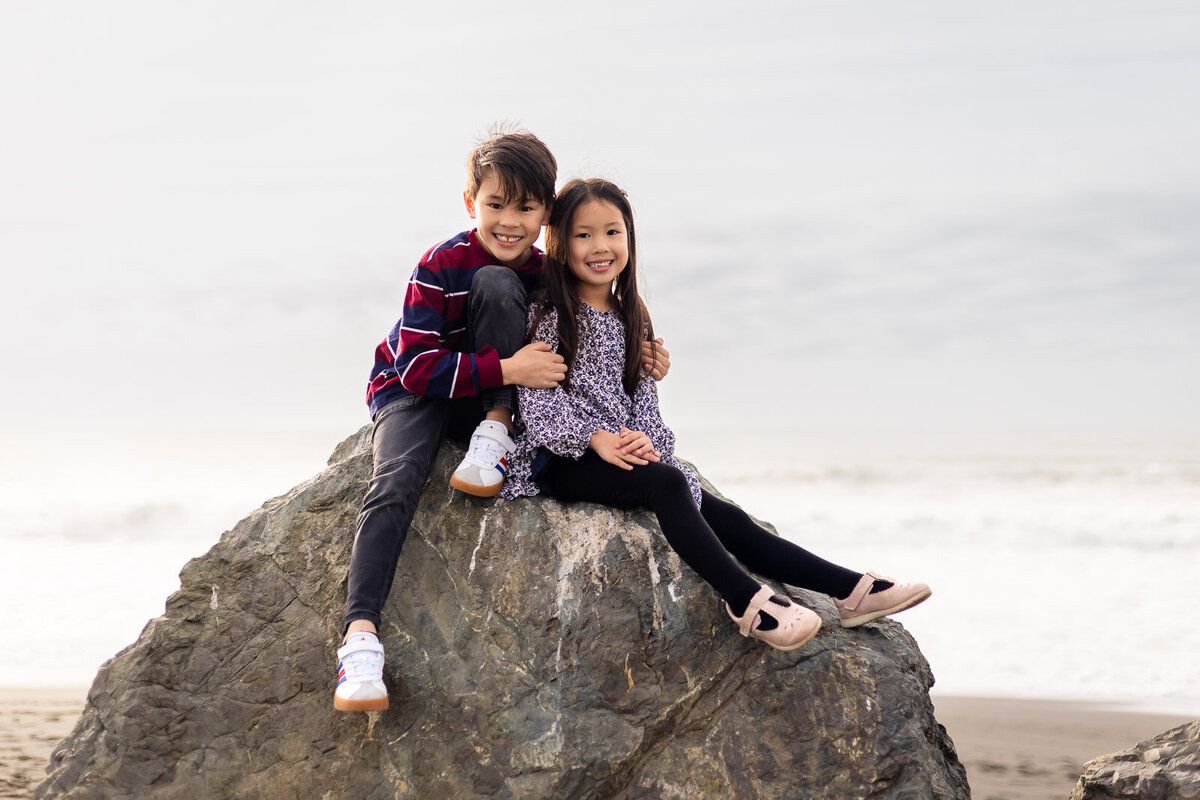 Siblings sitting on a large rock at Ocean Beach during Bay Area school photography lifestyle session – Ellobelle Photography