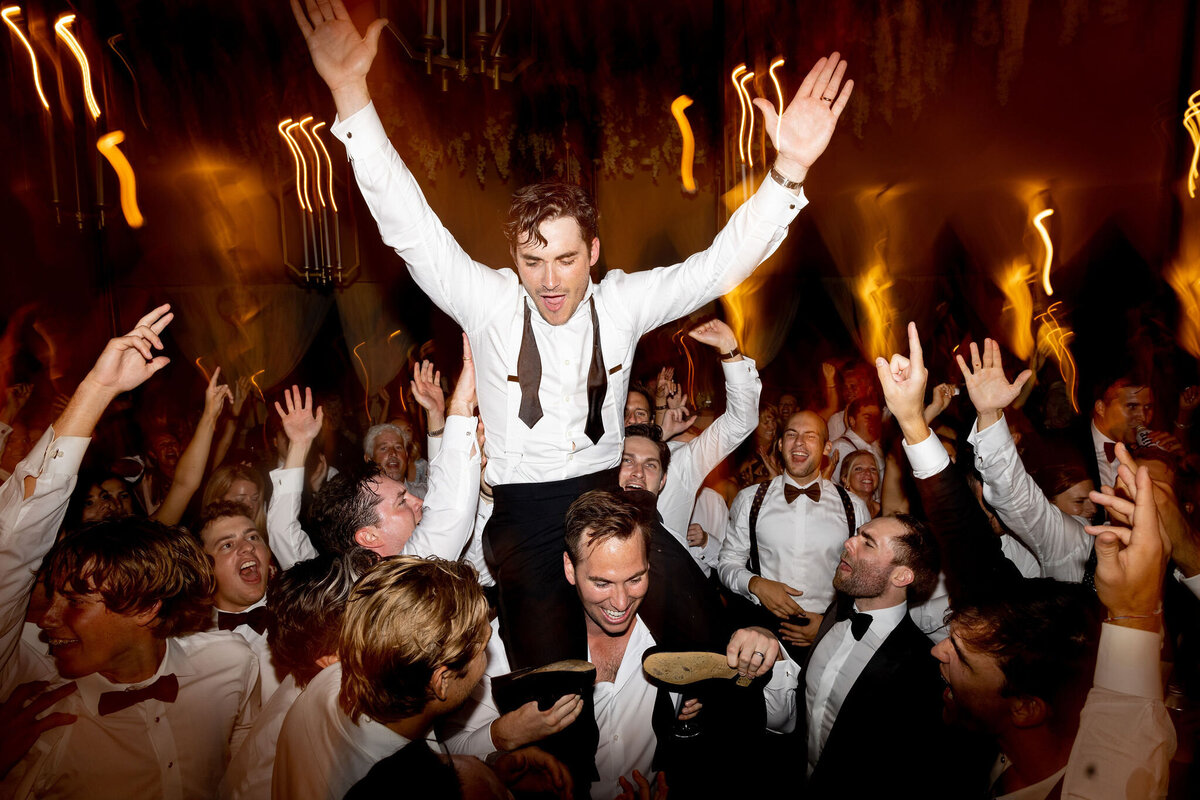 Picture of the groom on the shoulder of one of the groomsmen on the dance floor. 