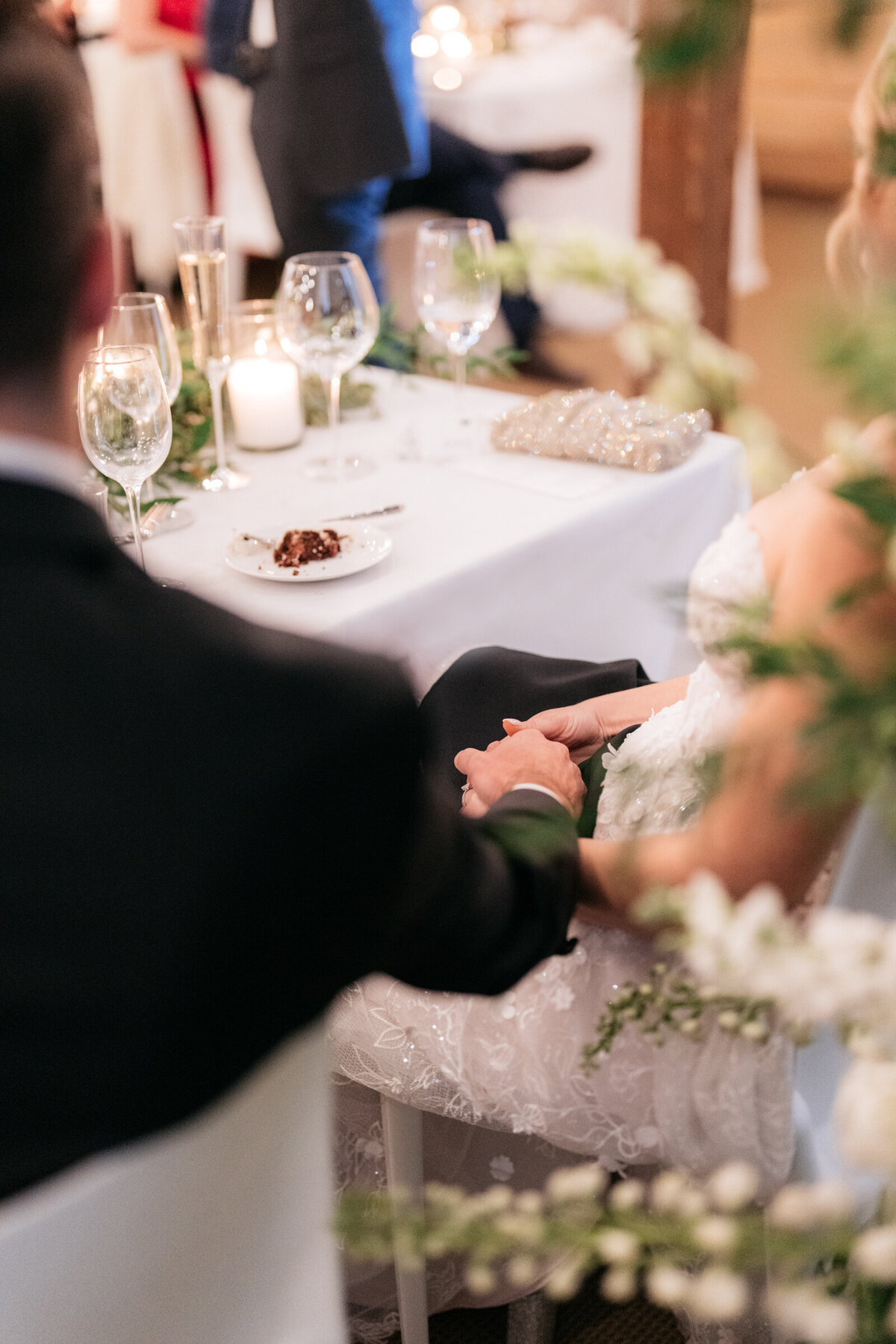 bride and groom secretly holding hands at wedding reception