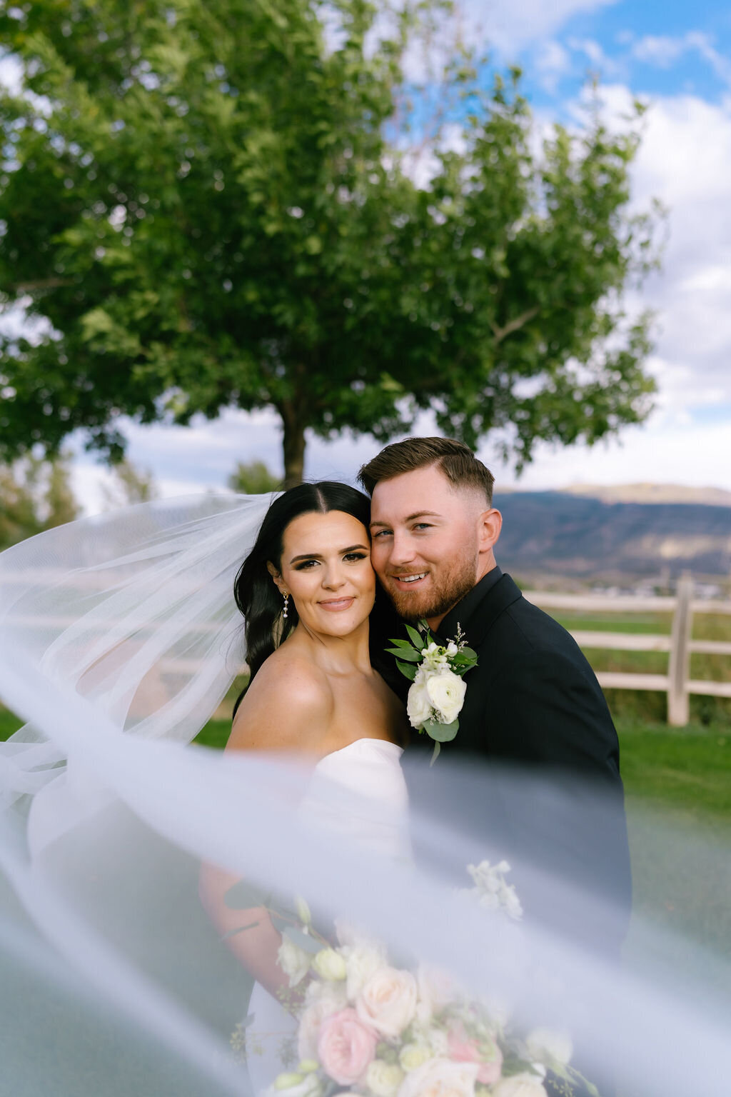 Couple close together beneath the veil
