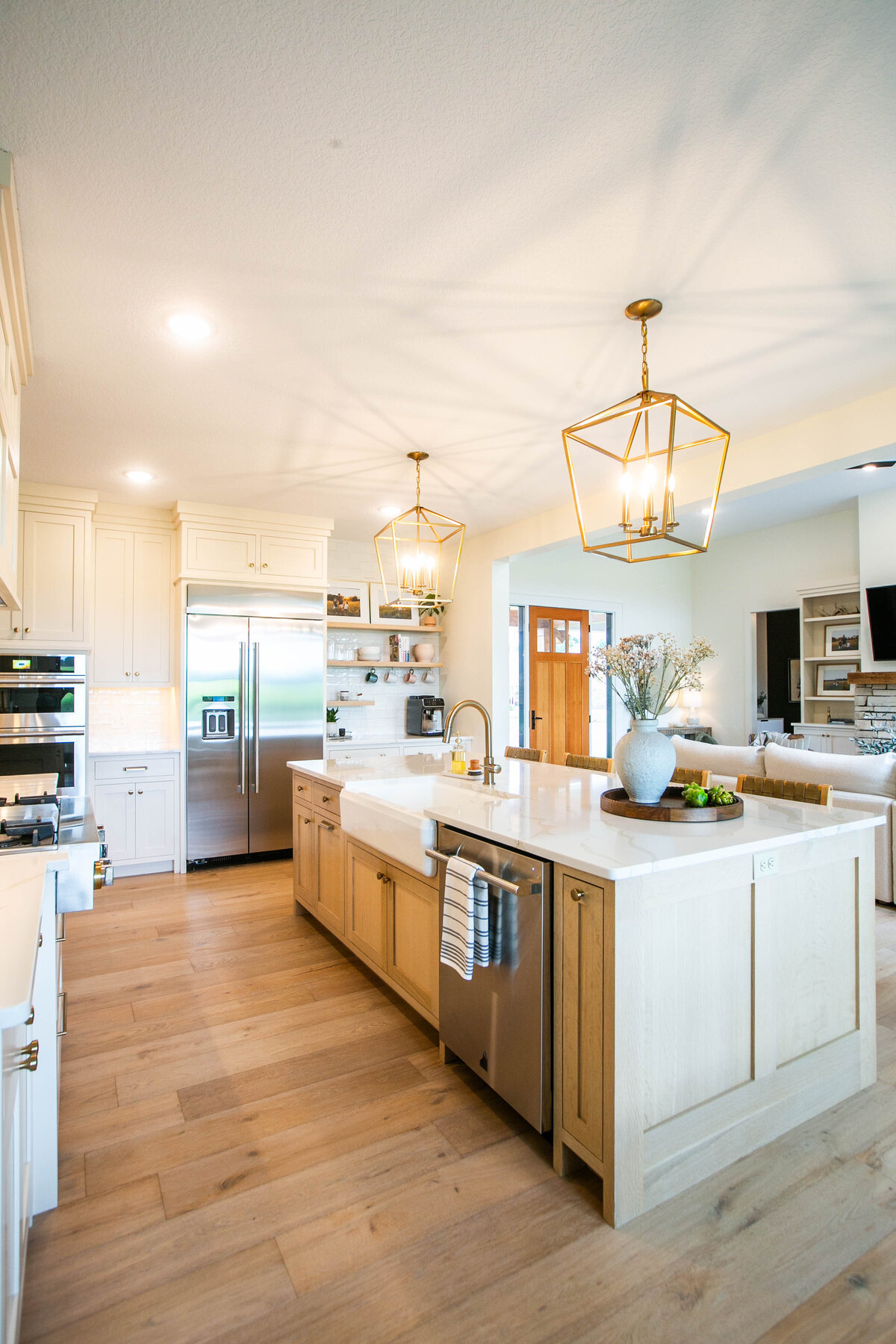 Open kitchen with white cabinets, large island, and quartz countertops in an Otsego custom home