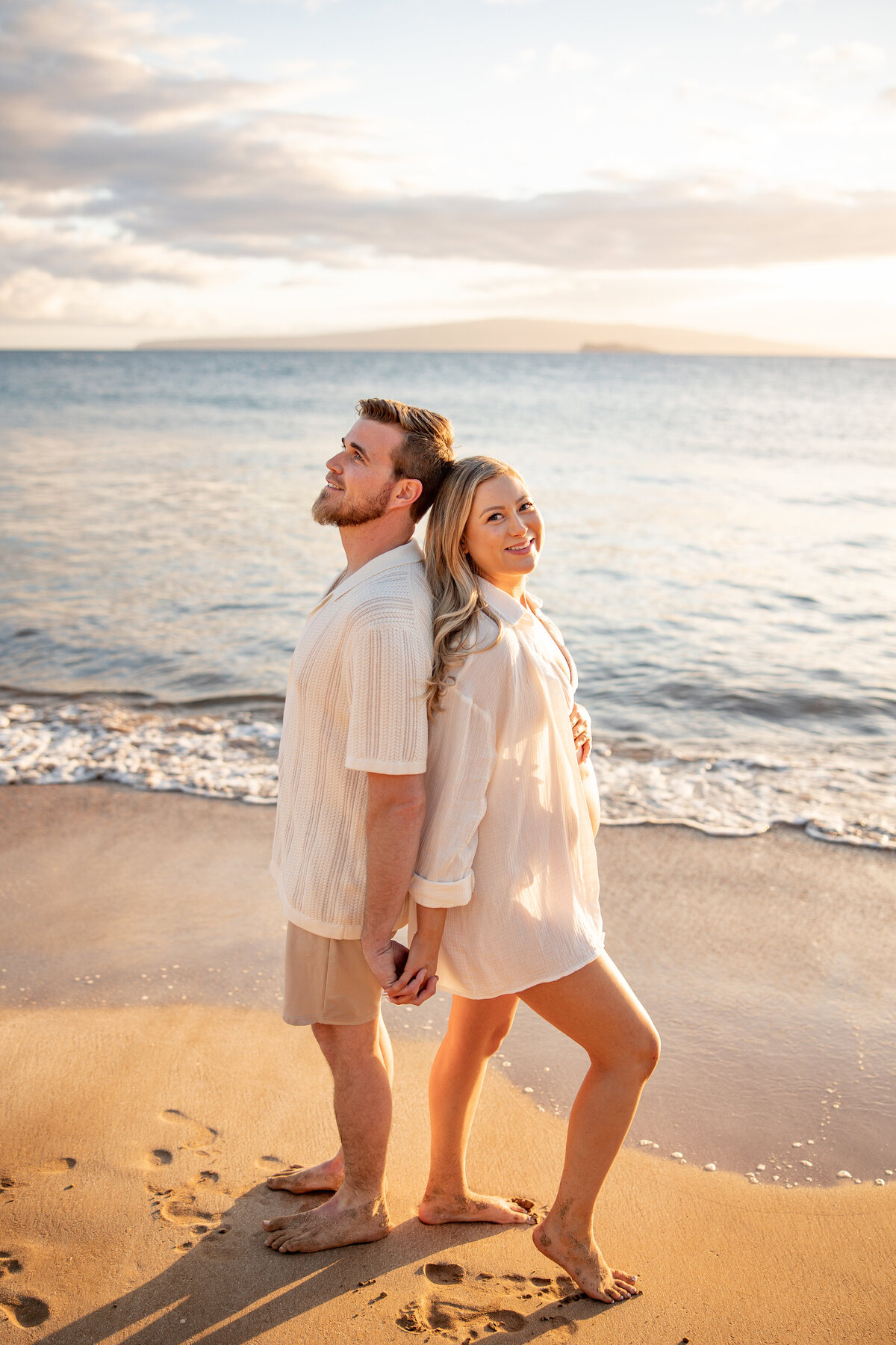 Maui Couples Photographer captures beach maternity photos with couple standing back to back