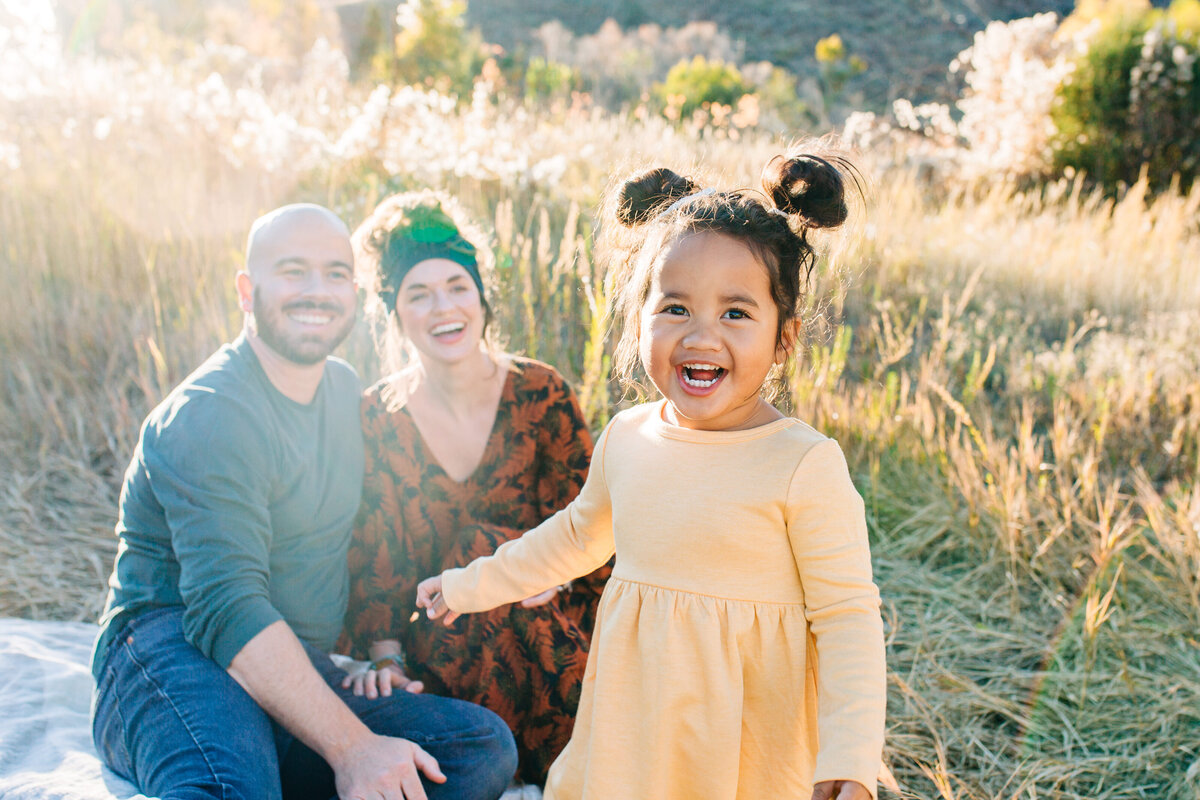 young girl laughing with parents during family photos