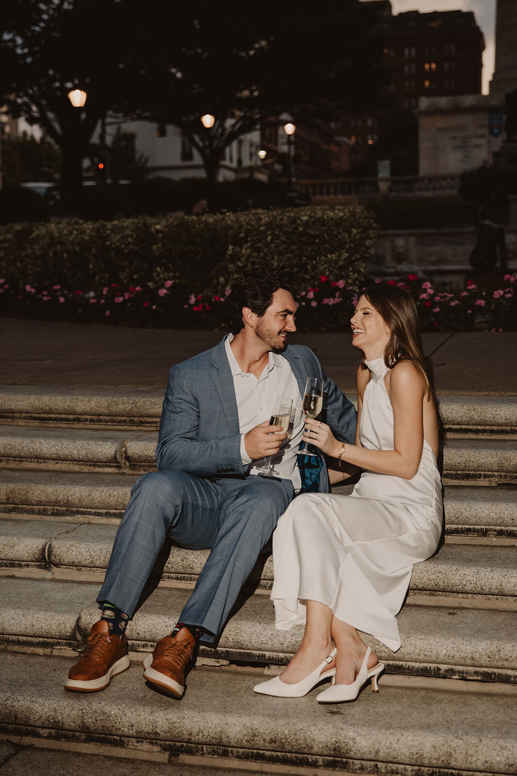 A couple sitting on stairs holding glasses of champagne 
