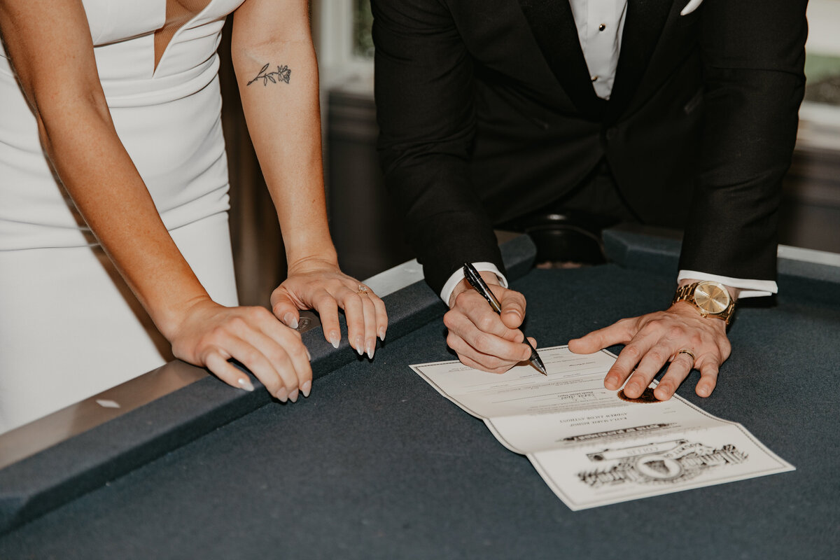 Wedding Photographer & Videographer, bride and groom signing marriage certificate