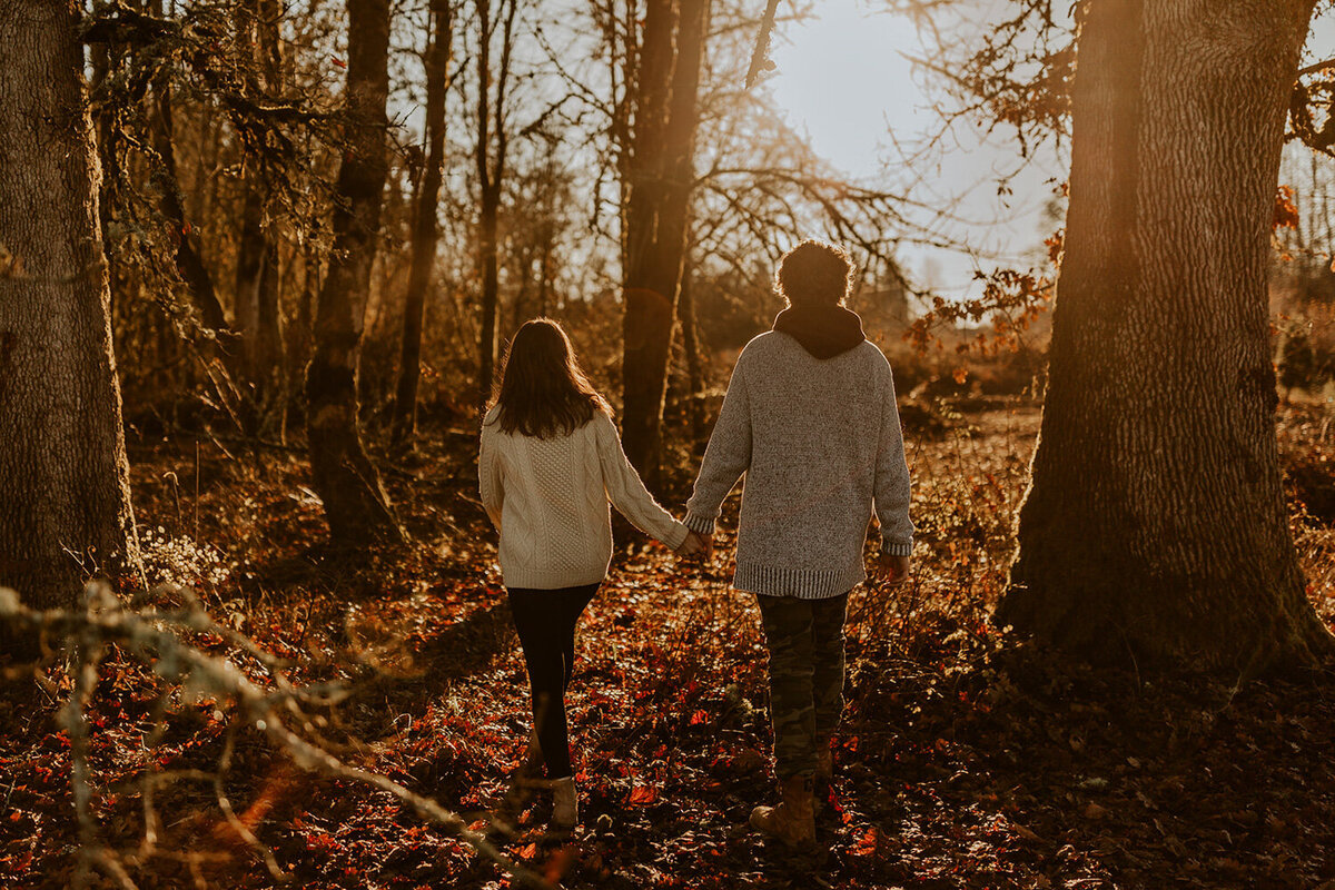 Couple walking towards the trees while holding each other's hand