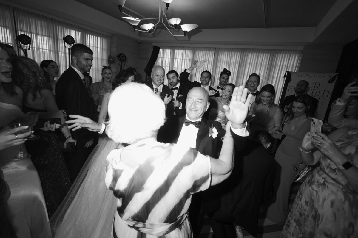 Bride and guests dancing with raised hands during celebration

