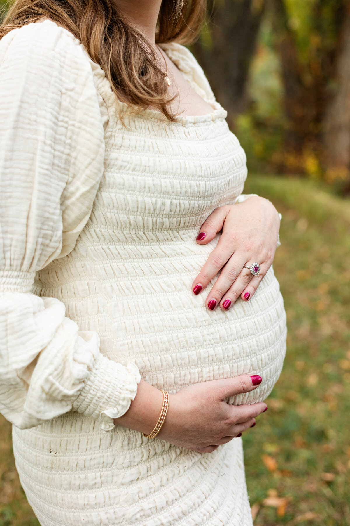 Close-up of a pregnant woman's belly. One of her hands is on top of the belly and one is underneath.