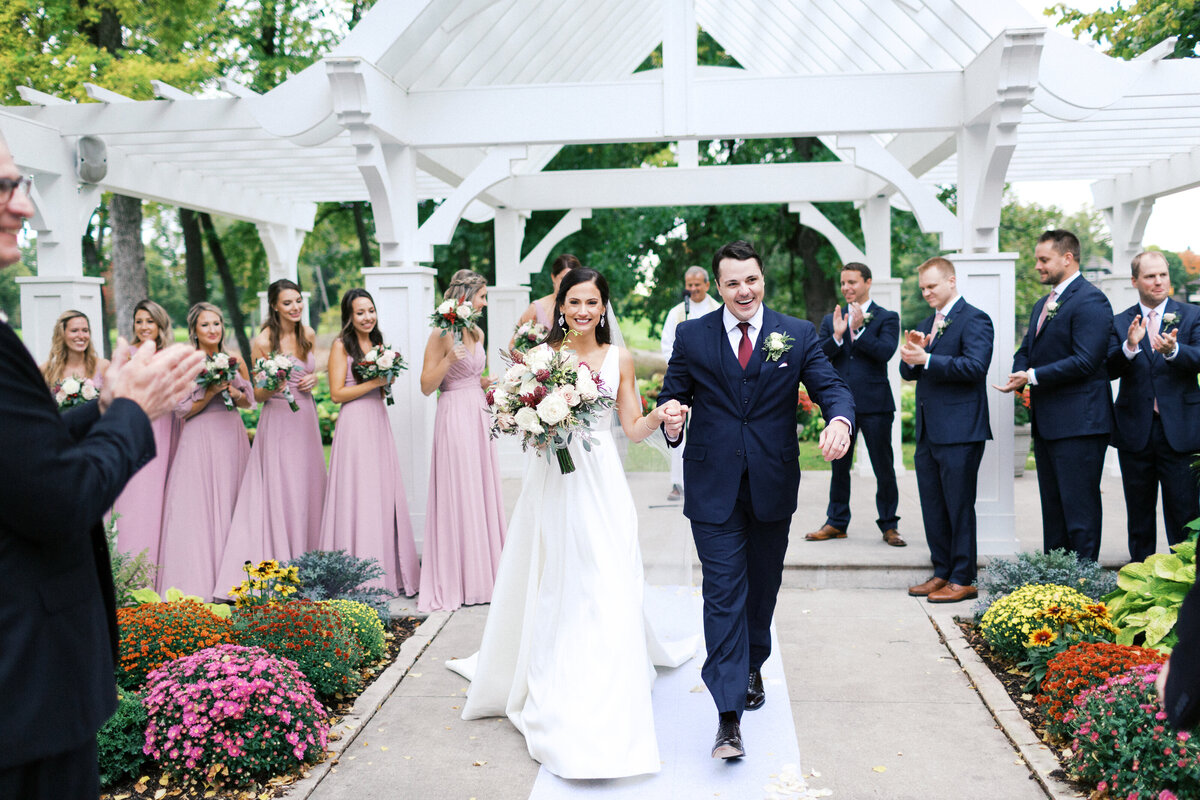 Newlyweds walking down the aisle with joy after their ceremony at Bearpath Golf & Country Club