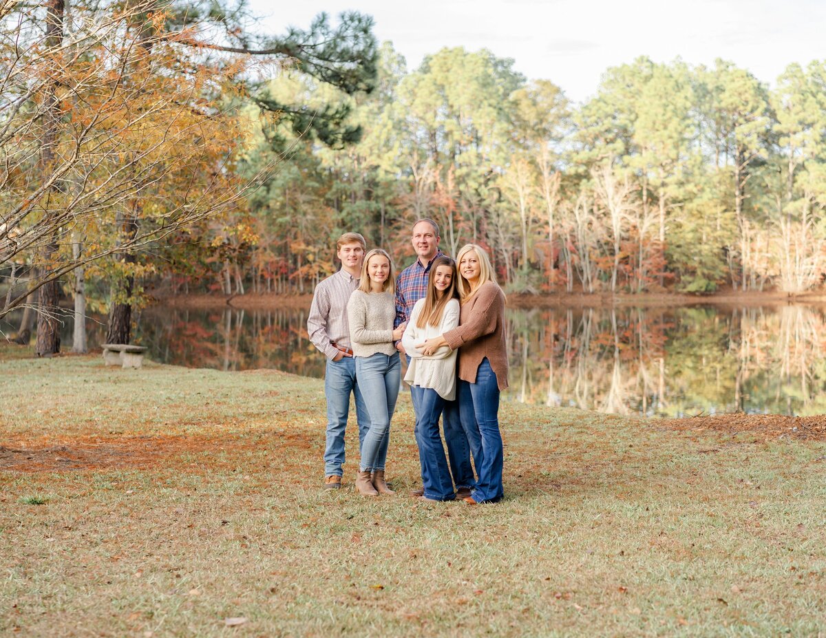 parents hugging childen at their autumn family photo shoot taken at their pond in their backyard