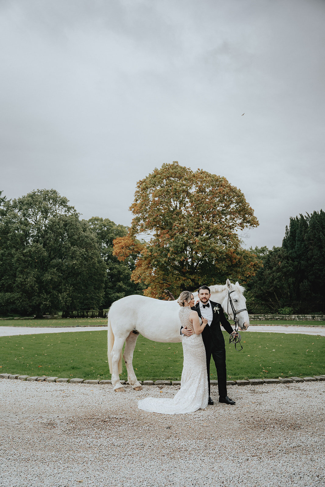 Bride looking at husband in front of white horse