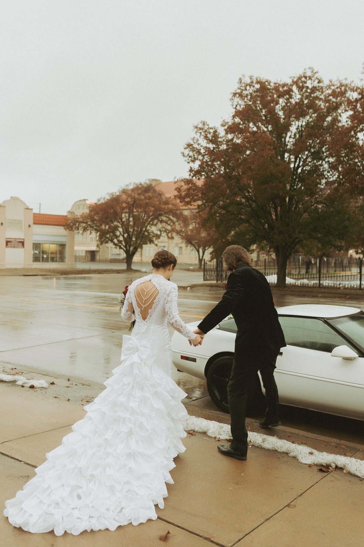 groom helping bride into getaway car