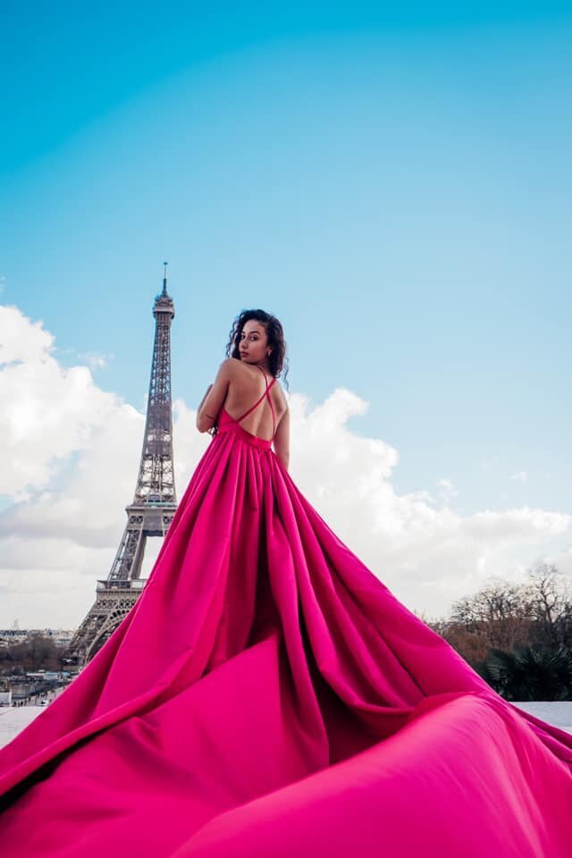 Women wearing a pink flying dress in front of the eiffel tower