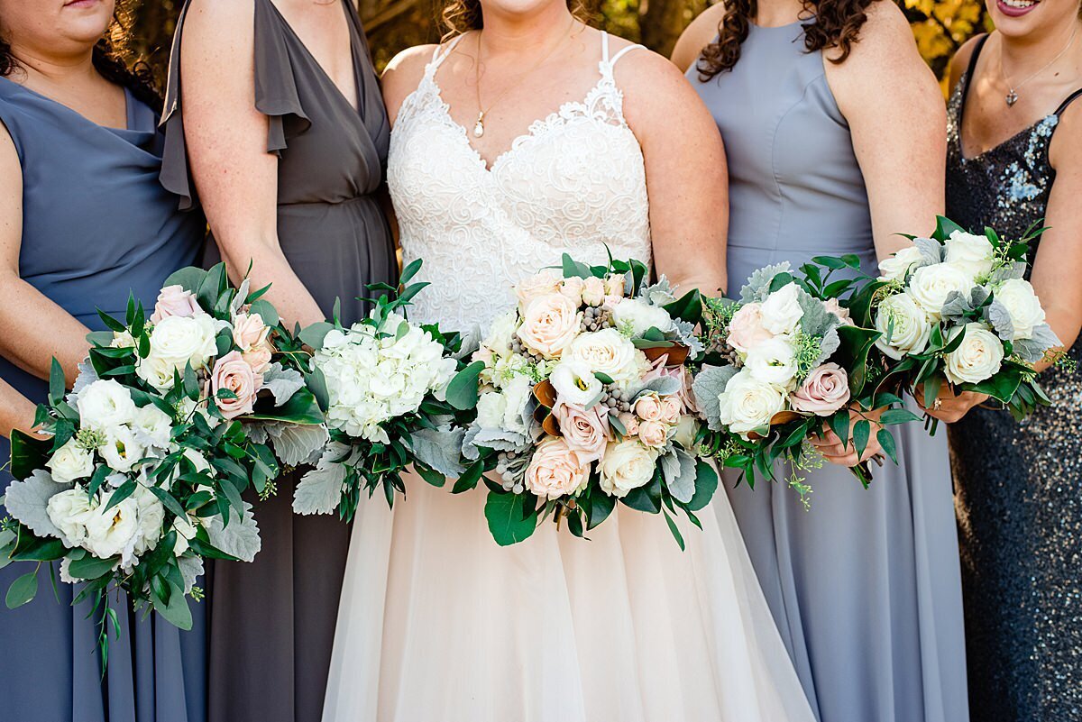 bridesmaids wearing mismatched dresses in shades of blue with white bouquets