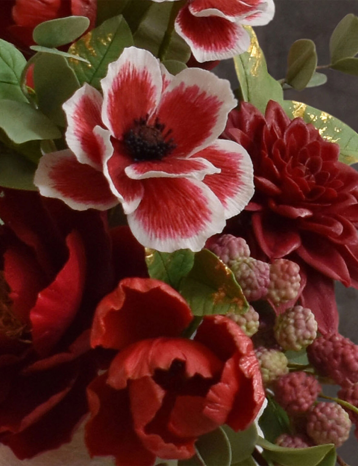 Rich red sugar flowers including a dahlia, poppies and parrot tulips
