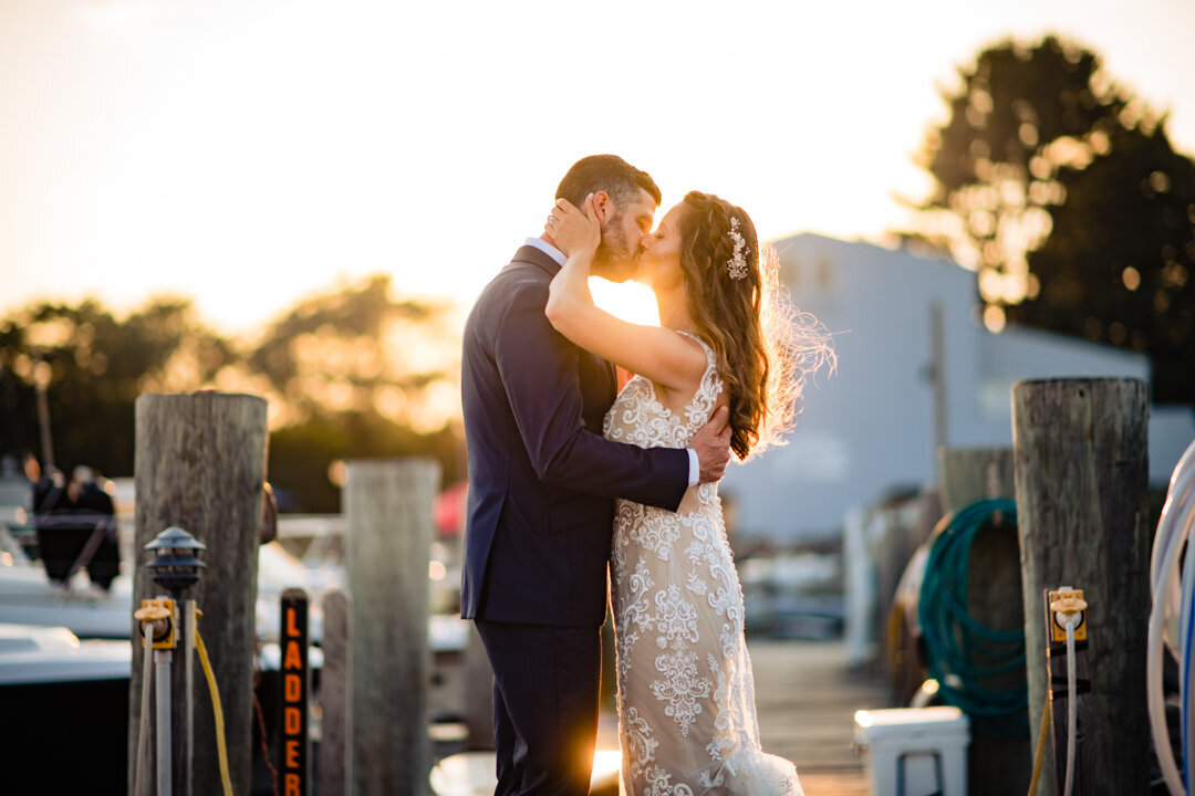 bride and groom embrace at sunset on the docks at their mystic yachting club wedding