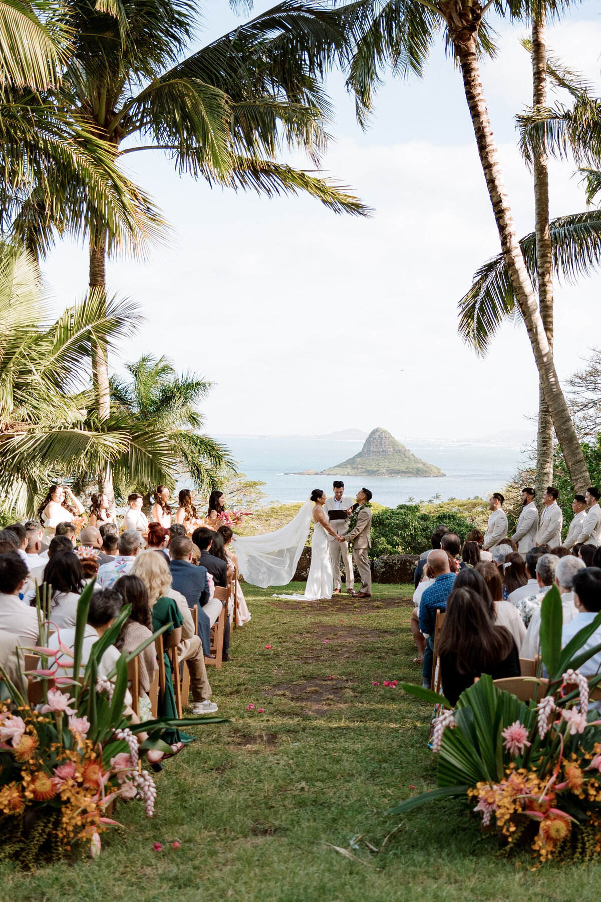 A lush film photograph of a wedding ceremony at Paliku Garden, nestled beneath the Koʻolau Mountains on Oʻahu, captured in Kate Winters’ nostalgic documentary style