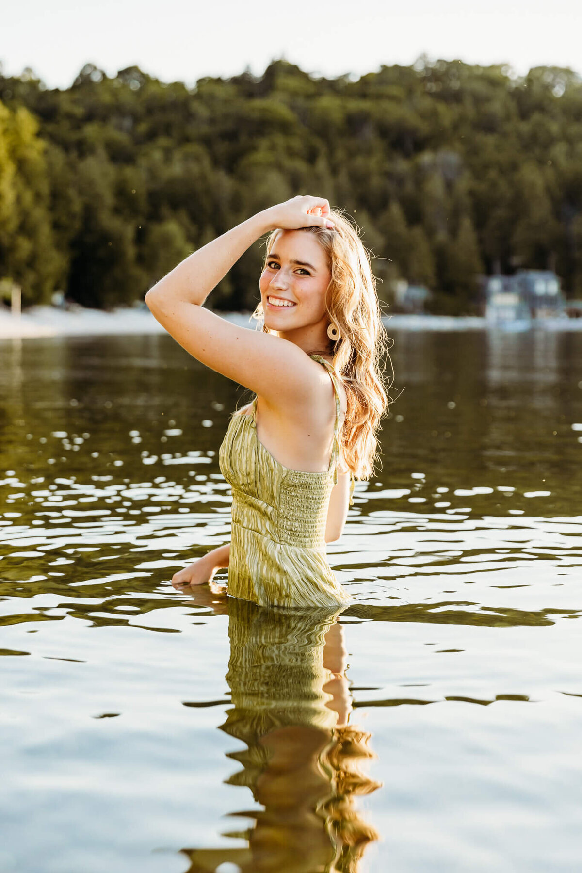 Teen girl posing in the water as she pulls her hair back