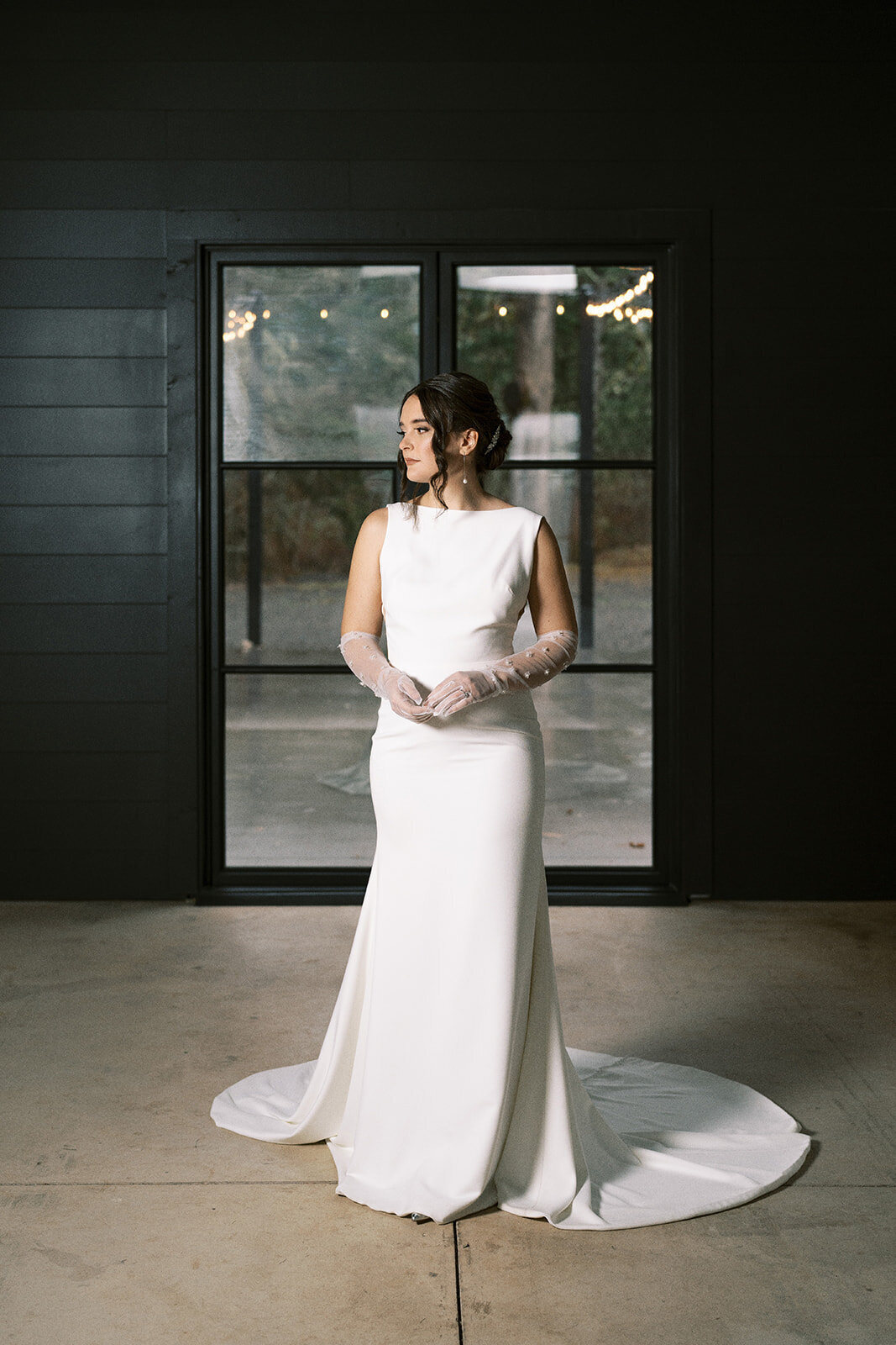 A bride stands in front of a glass door looking to the side at Sage and Social venue in Mulino Oregon.