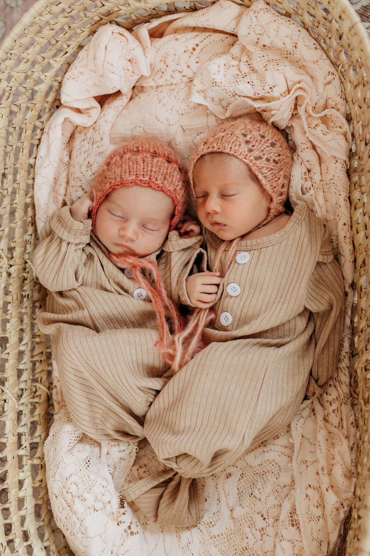 twin girls with bonnets snuggled in moses basket by harrisburg pa newborn photographer