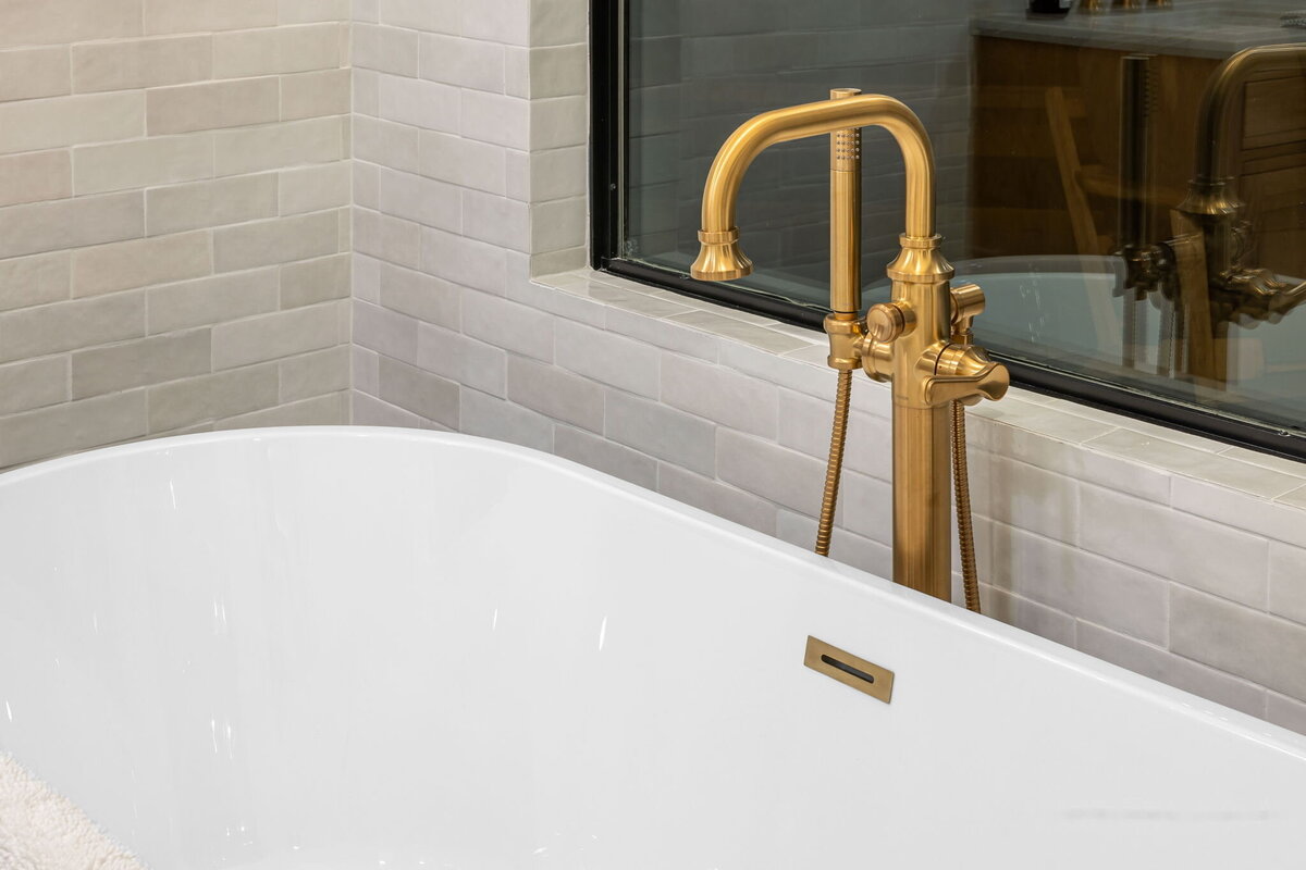 Golden tap into a large white bath tub