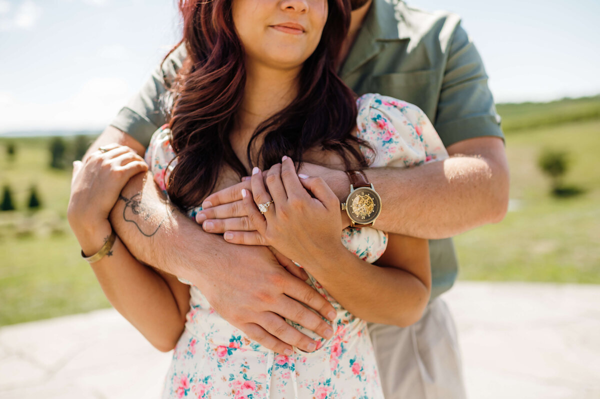 detail shot of man holding woman from around the shoulders while she holds his hands and smiles gently captured by Virginia wedding photographer