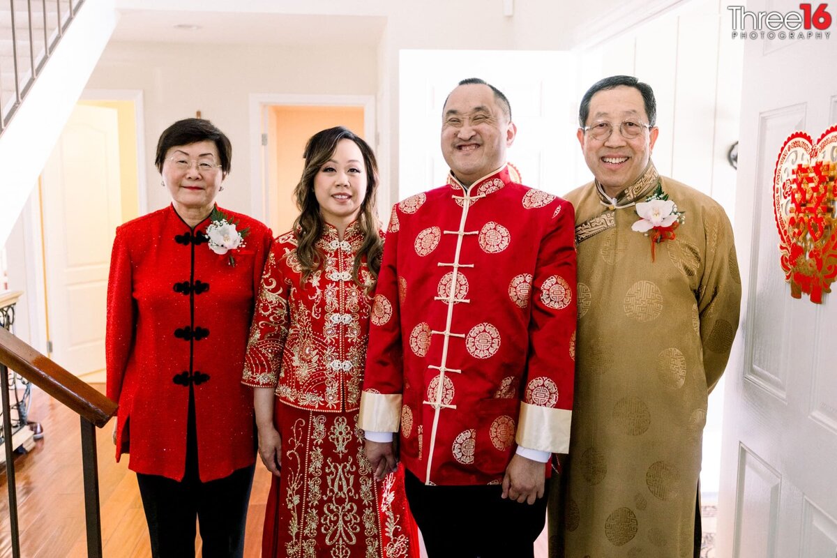 Bride and Groom dressed in traditional Chinese wedding red outfits pose with parents after the wedding