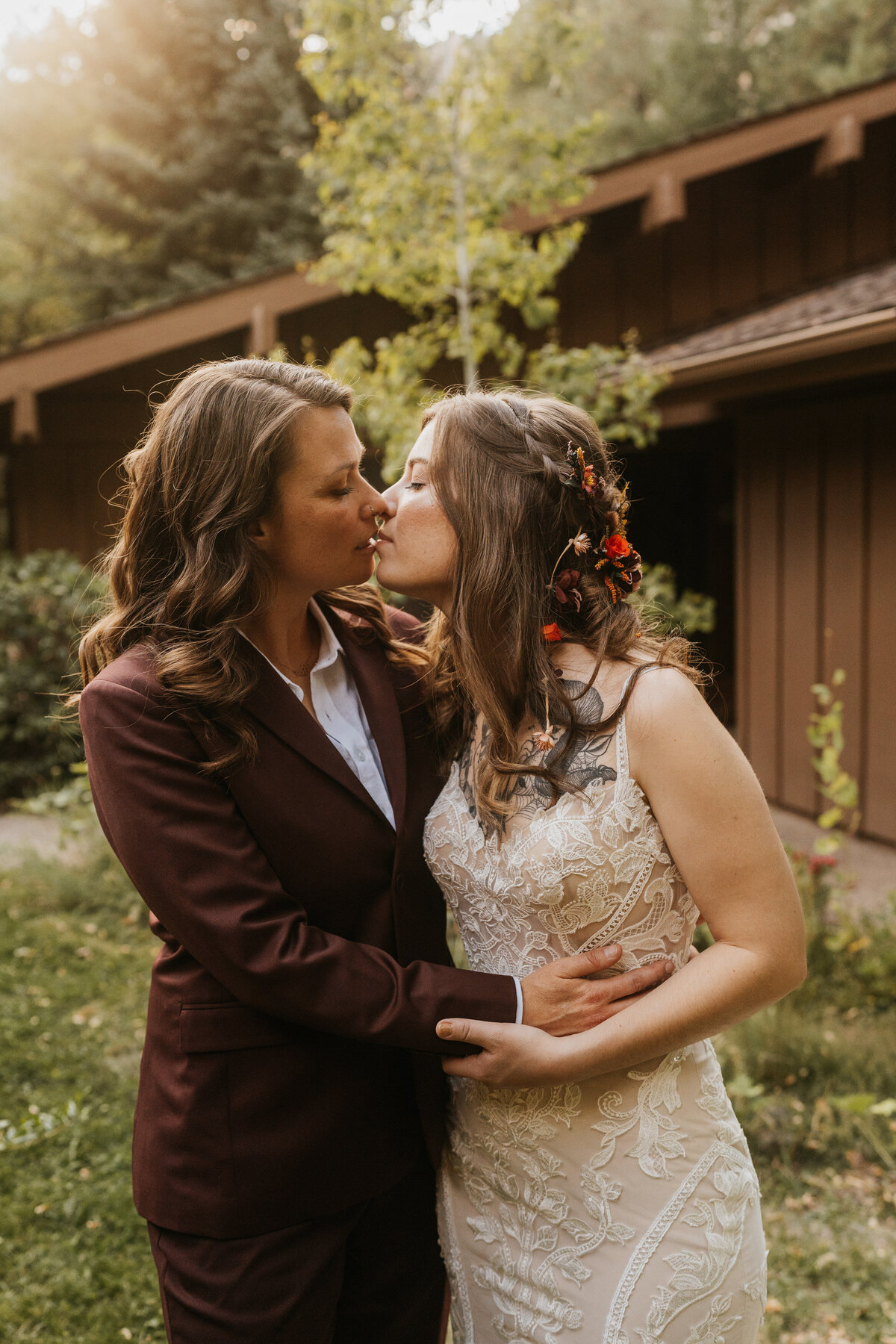 A newlywed couple with their arms around each other as they lean in for a kiss