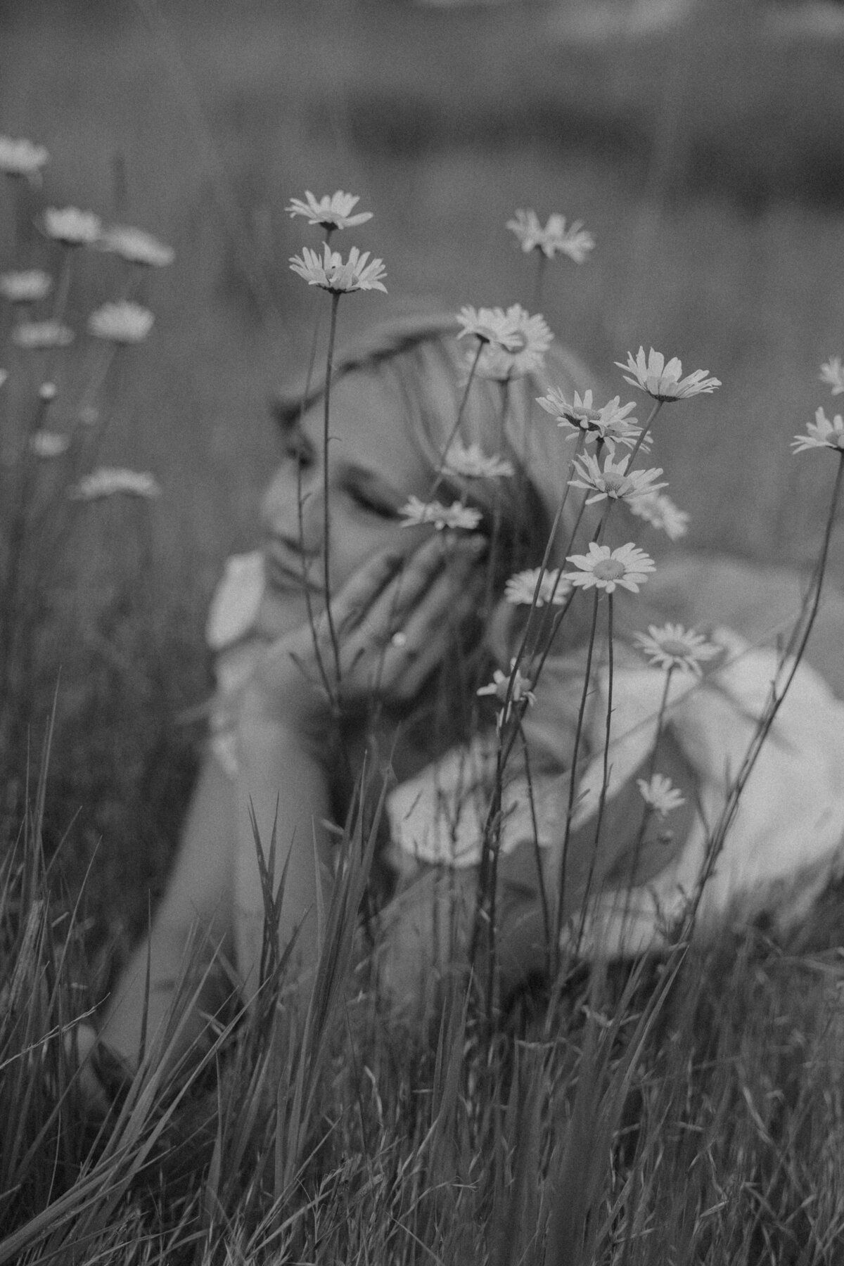 Western Senior Portrait of Girl Sitting in Tall Grass Wearing Denim Skirt and Cowboy Boots