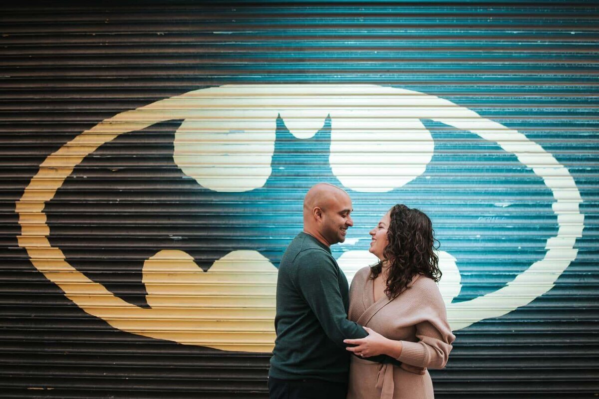 Couple looking at each other while being backlit by a batman wall in Philadelphia