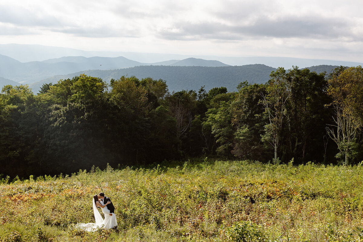 A couple kissing in a small field in the mountains