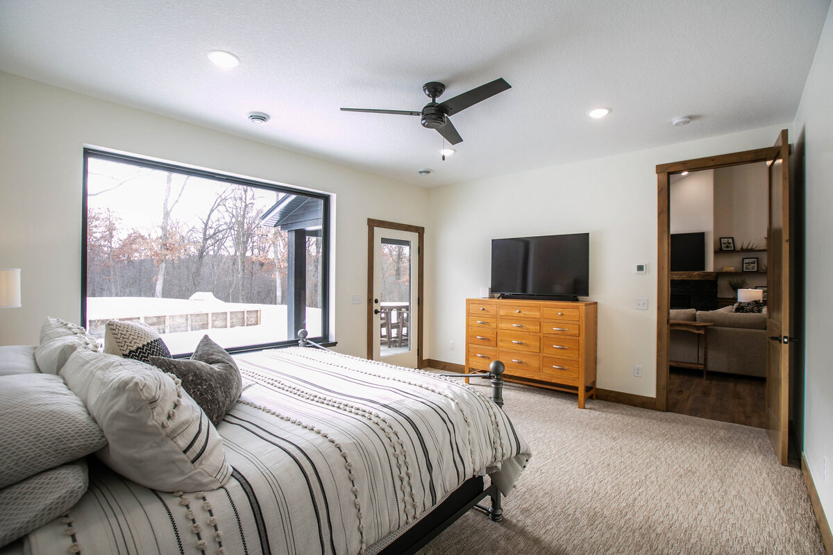 Spacious primary bedroom in custom Otsego home with natural light and dark wood accents