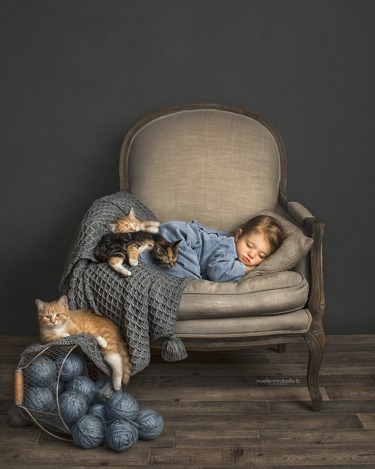 Baby dressed in blue romper sleeping in vintage french chair with three little kittens.